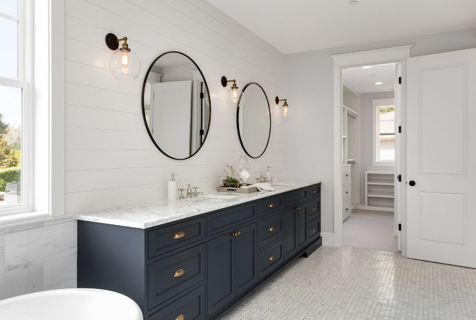 A sleek navy and white bathroom vanity paired with minimalist round mirrors.