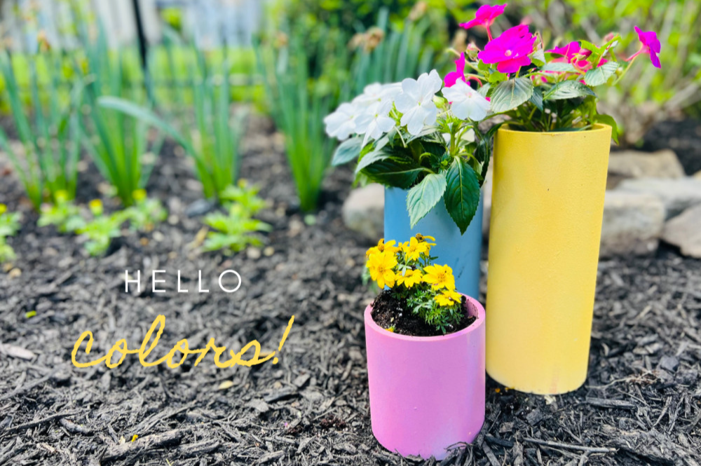 Three PVC pipe planters in a garden.