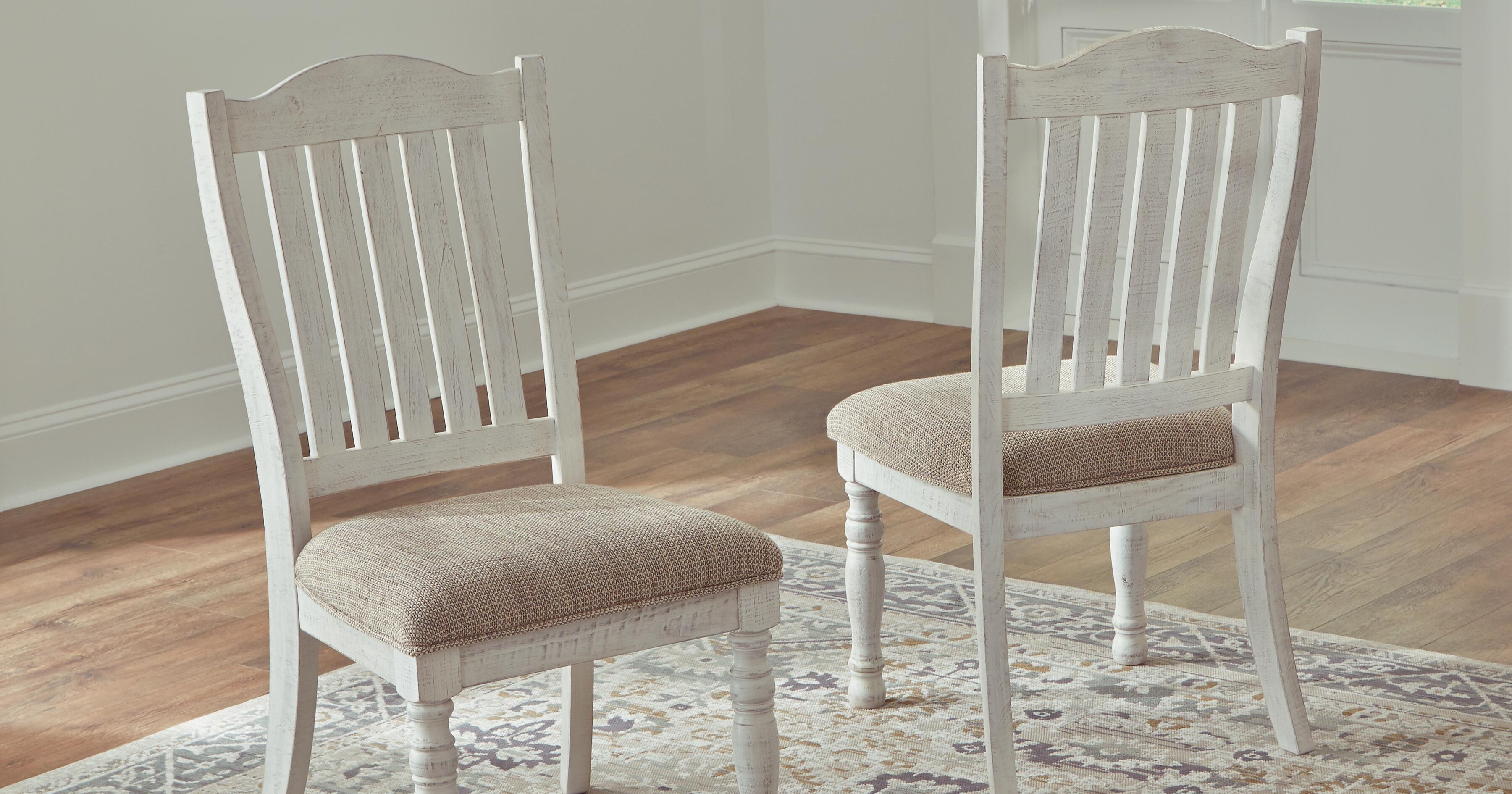 White upholstered dining chairs with a tan cushioned seat.