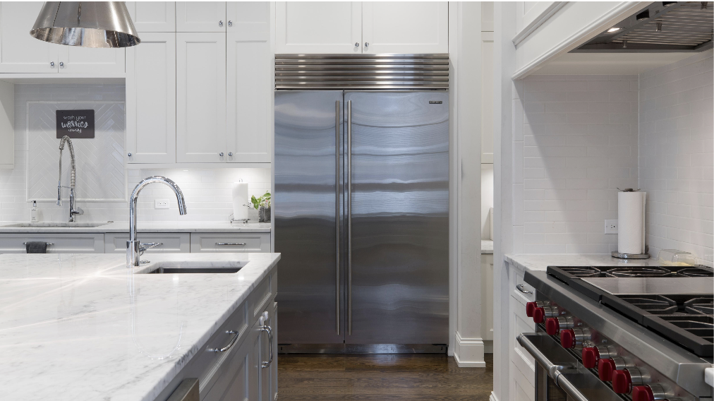 A large kitchen with white cabinets and a large silver side-by-side refrigerator.